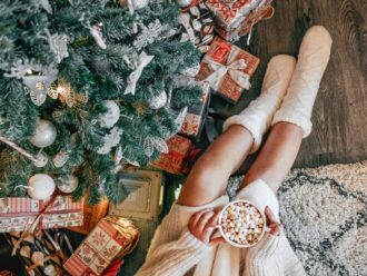 overhead shot of a christmas moment young woman in a cozy sweater sitting by a christmas tree woman t20 pR3p6j